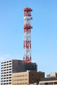 Low angle view of crane by building against sky