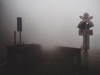 Information sign on railroad tracks against sky