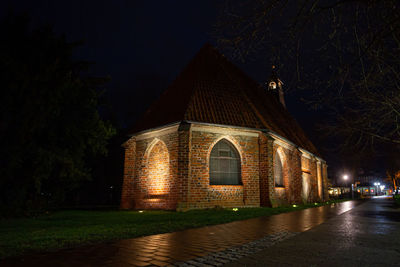 Illuminated building by trees at night