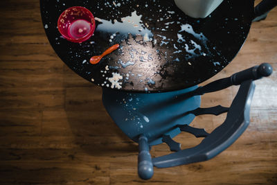 Big mess of spilled milk and cereal on table with empty bowl and spoon