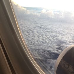 Cropped image of airplane flying over sea against sky