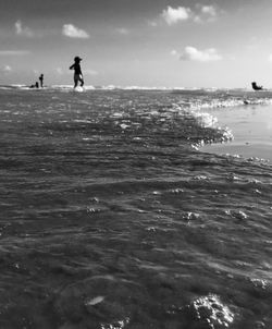 People in calm sea against sky