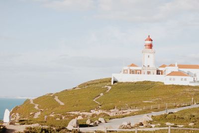 Lighthouse amidst buildings against sky