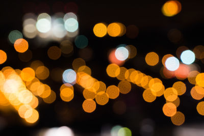 Defocused image of illuminated lights against black background