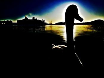 Silhouette woman standing by lake against sky during sunset