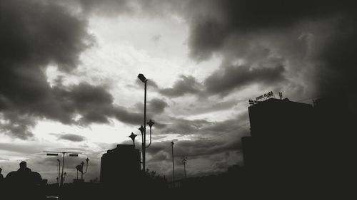 Low angle view of silhouette buildings against cloudy sky