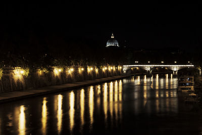 Illuminated bridge over river at night