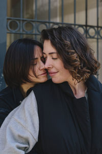 Affectionate lesbian woman embracing young girlfriend from behind