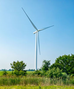 Low angle view of windmill against clear blue sky