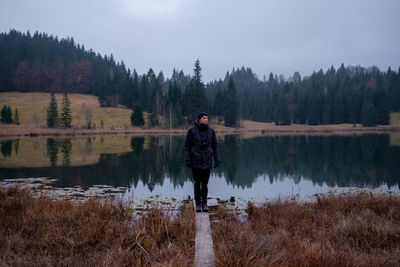 Man standing by lake against sky