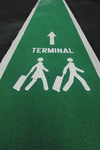 High angle view of text with human representation and arrow symbol on pathway at airport