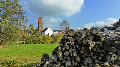 Stack of stones on field by trees against sky