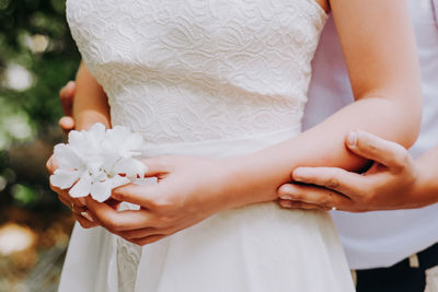 Midsection of woman holding white flower