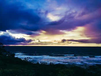 Scenic view of sea against dramatic sky during sunset