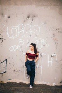 Portrait of a teenage girl standing against wall