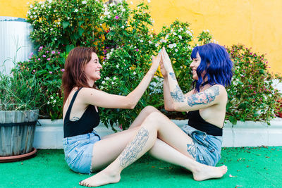 Happy young women playing patty cake in backyard