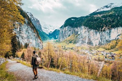 Rear view of person walking on mountain against sky