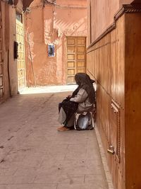 Side view of woman sitting on abandoned room