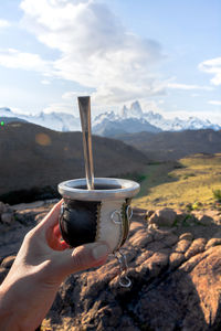Person holding mate against mountains