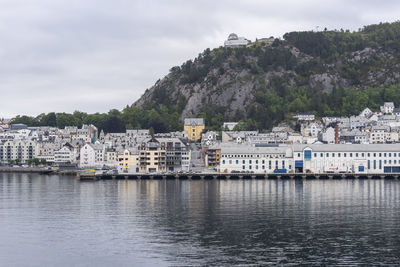 Buildings by river against sky in town