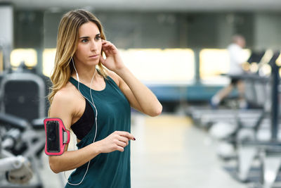 Woman listening music while standing in gym