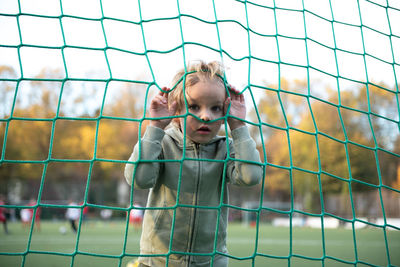 A boy croaks through a soccer net
