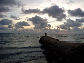 Silhouette person on beach against sky during sunset