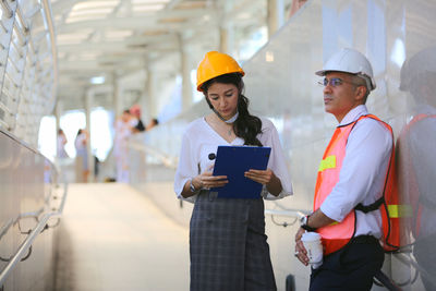 Engineers discussing over clipboard while standing on footbridge