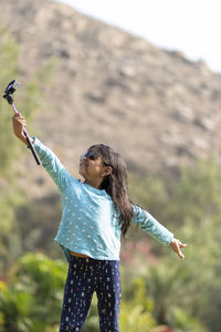 Woman with arms outstretched standing outdoors