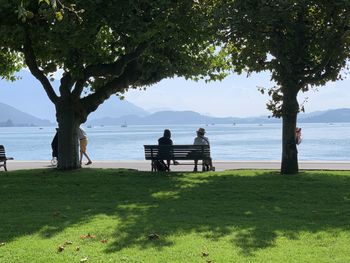 People sitting on bench by sea