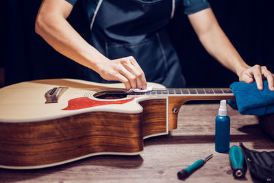 Midsection of man repairing guitar