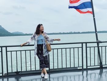 Woman standing by railing against sea