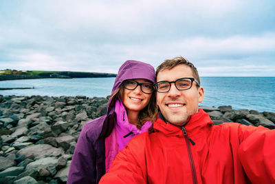 Portrait of smiling young woman standing against sea