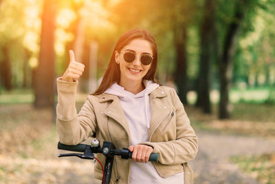 Portrait of young woman standing against trees