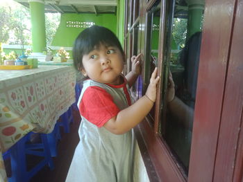 Cute boy looking through glass window