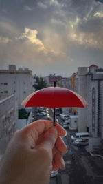 Person holding umbrella against buildings in city