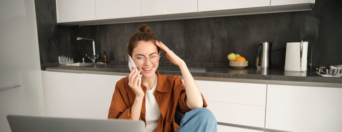 Young woman using mobile phone while sitting at home