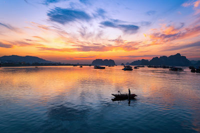 Silhouette boat in sea against sky during sunset