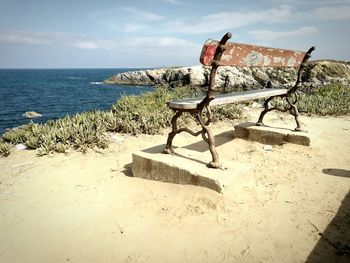 Deck chairs on beach against sky