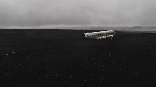 Abandoned boat on land against sky