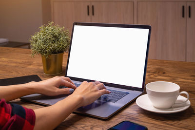 Cropped hands using laptop on table