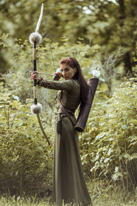 Woman standing on field against trees in forest