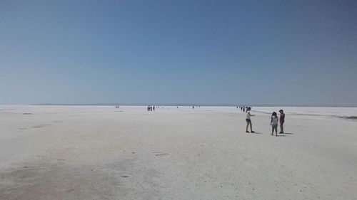 People on salt lake against clear sky