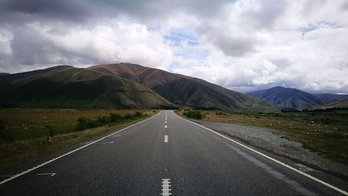 Road leading towards mountains against sky