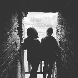 Rear view of friends standing against wall