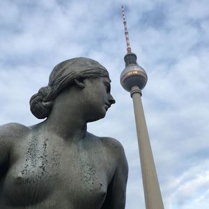 Low angle view of statue and fernsehturm tower against sky