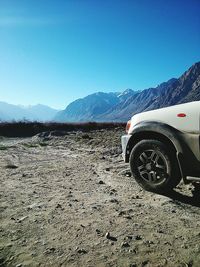 Car on desert against clear sky