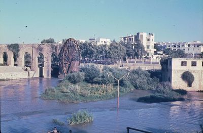 Arch bridge over river against buildings