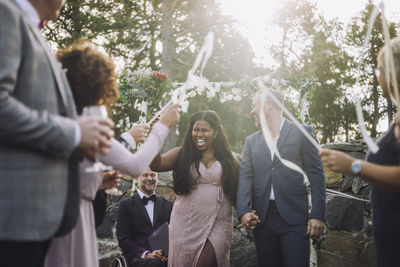 Newlywed bride holding hand of groom while walking amidst guests at wedding ceremony