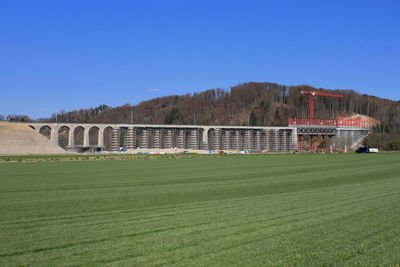 Built structure on field against clear blue sky